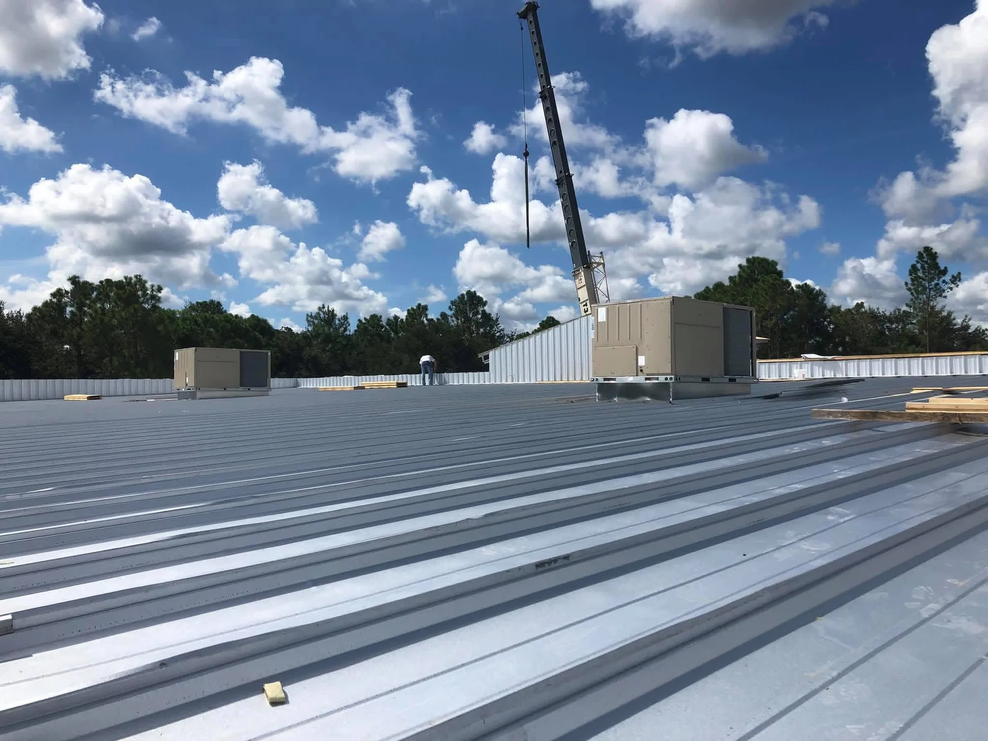 Commercial HVAC rooftop units and crane on a metal-roof building in Polk County FL